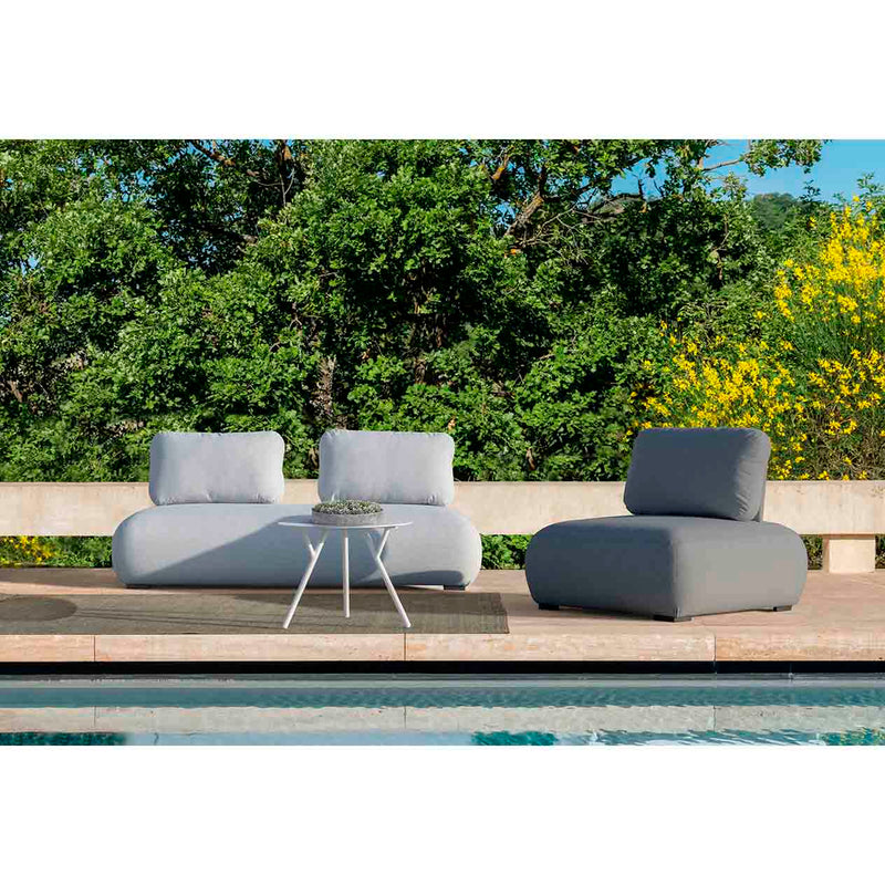 Light grey Iowa 2-seater upholstered lounge, a single upholstered lounge, and a matching round aluminium coffee table arranged poolside for three people. Set on a sunny summer day with lush greenery in the background, this stylish setup offers the perfect example of outdoor living, ideal for relaxing and enjoying the surroundings.