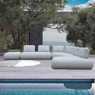 Light grey Iowa 6-seater outdoor upholstered modular lounge set on a wooden deck, accompanied by a large round rug. Surrounded by trees and with mountains in the background, this contemporary setup perfectly blends comfort and style in outdoor living, enhancing the sleek exterior of the modern house.