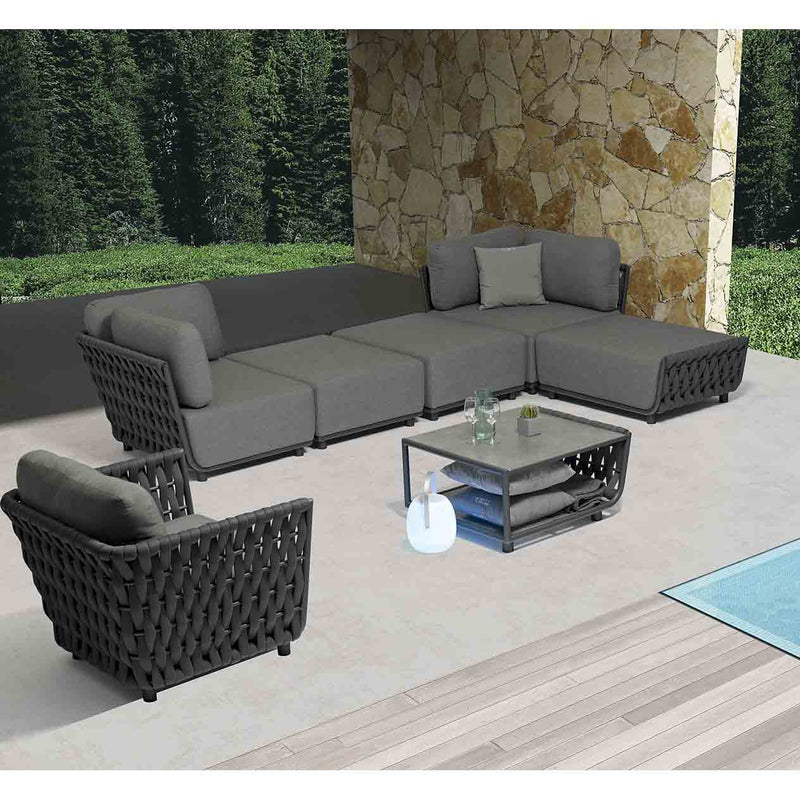 Six-seater rope modular lounge with matching coffee table, set in a sunny outdoor area with lush greenery in the background, ideal for outdoor living.