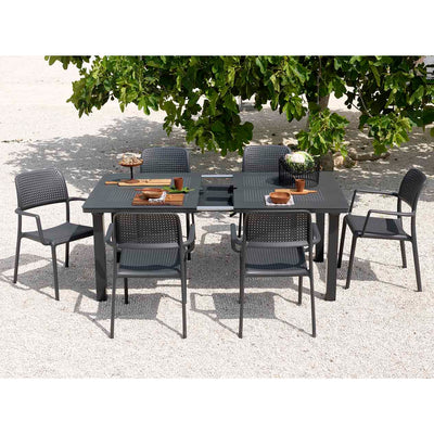 Black resin extension dining table with six matching chairs, set in an outdoor area as alfresco furniture, with the table styled with wooden cutlery for a refined look.