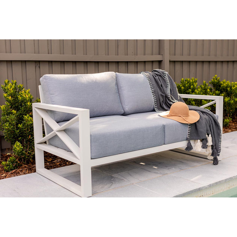 Outdoor furniture collection including aluminum outdoor lounge chair, two-seater, and three-seater sofa next to a swimming pool, part of the Linear Lounge range in white.