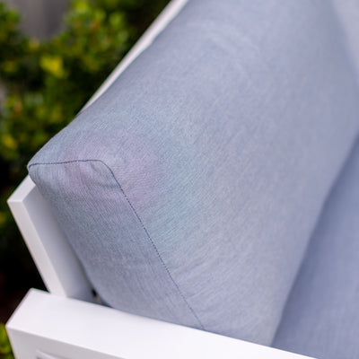 Close up of a white aluminum outdoor lounge chair from Linear Lounge collection with a blue pillow, part of outdoor furniture set.