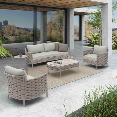 Boston Outdoor Rope Coffee Table with two wine glasses and a rolled-up magazine on it, surrounded by two Boston Outdoor Rope Armchairs and a Boston 2-Seater Outdoor Rope Lounge, all in beige, set in the backyard of a super modern house, exemplifying elegant alfresco furniture.