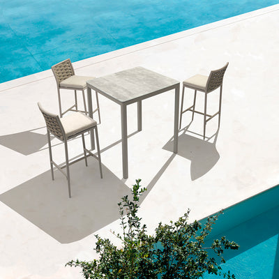 Three beige Boston Outdoor Rope Bar Stools paired with a sleek bar table, set poolside in a stylish modern European house outdoor area, perfect for luxurious outdoor living.