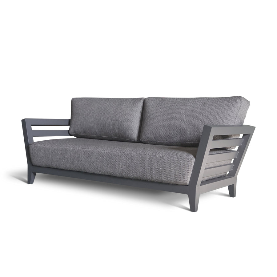 Grey 3 seater sofa with light aluminium legs set in a modern concrete industrial outdoor setting.