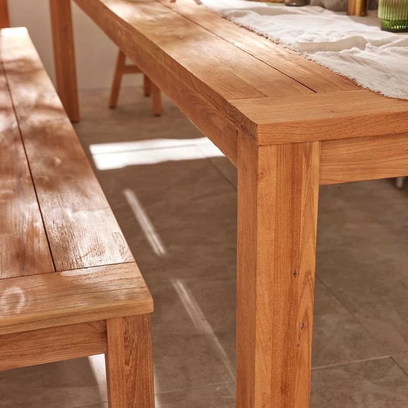 Outdoor furniture: A recycled teak dining setting with natural frame set against a beige background with a bit of sunlight coming in. This Polly dining table, available in two sizes, is perfect for outdoor dining furniture and outdoor balcony furniture.