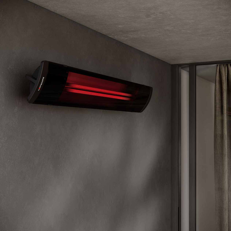 A sleek black Heatscope Outdoor Pure+ 3000W electric radiant heater mounted against a concrete grey wall, creating a moody ambiance for outdoor living.
