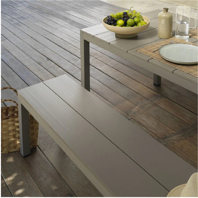 A brown Nardi Rio outdoor bench with a matching table, set with fruit and cutlery, placed on a wooden deck outdoors, creating a stylish and functional alfresco furniture setup for outdoor dining and relaxation.