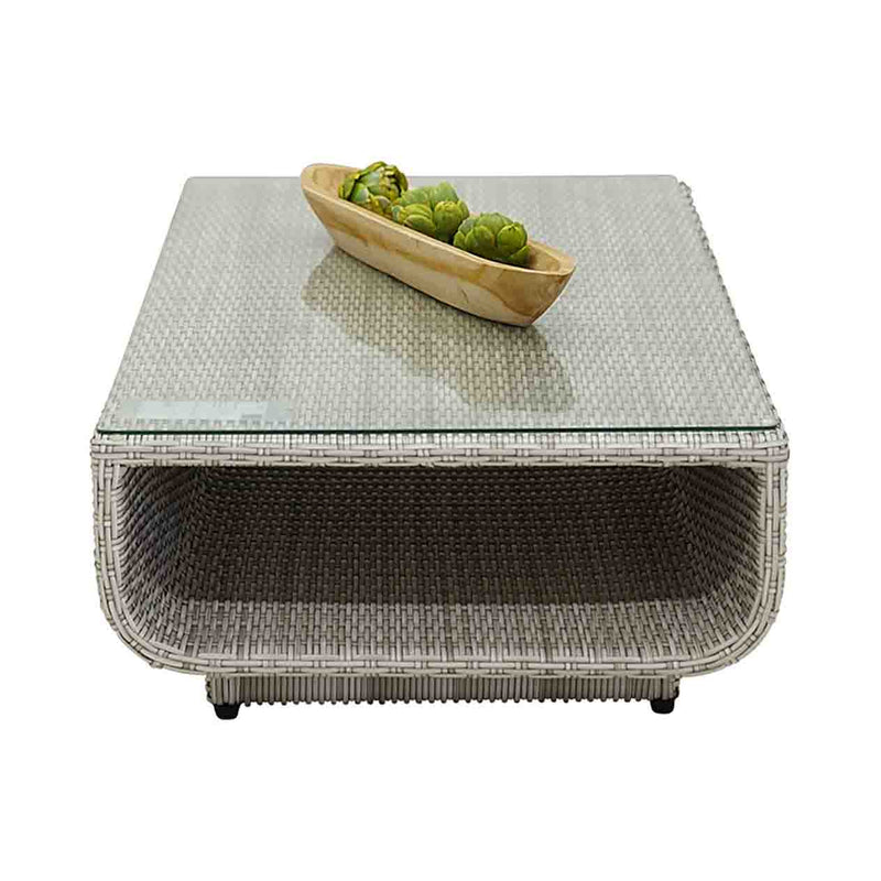 Outdoor furniture Rossland collection featuring wicker lounge chair, sofas, and a glass table with a bowl of broccoli on it.