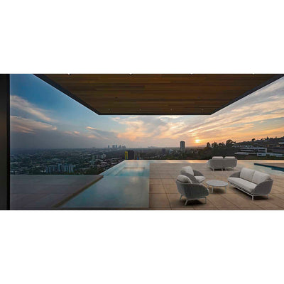 Sorrento 5-seater outdoor lounge setting with a coffee table, set in the outdoor area of a modern house, with the sun setting in the background, creating a moody and inviting atmosphere perfect for outdoor living.