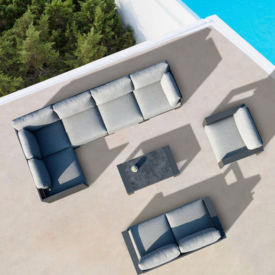 Top-down view of the Skyline coffee table surrounded by a three-piece modular lounge seating eight, with a pool and trees visible in the background, showcasing elegant alfresco furniture for outdoor relaxation.