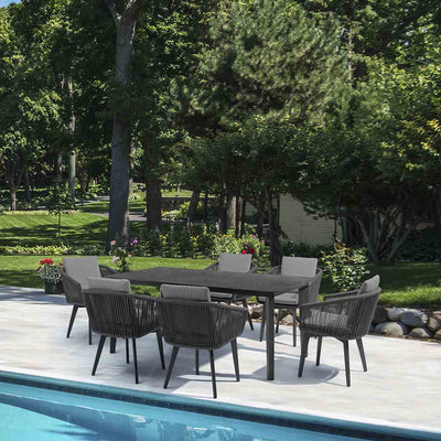 Black Truro outdoor aluminum dining table with a ceramic glass top, accompanied by six matching outdoor rope chairs, set poolside on a sunny day with vibrant greenery in the backgroundan ideal combination of alfresco furniture for elevated outdoor living.