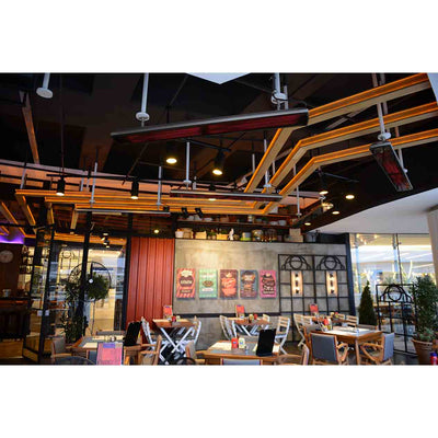 Multiple Heatscope Outdoor Vision 3200W heaters mounted overhead in a trendy restaurant, providing warmth for customers in a stylish outdoor living area.