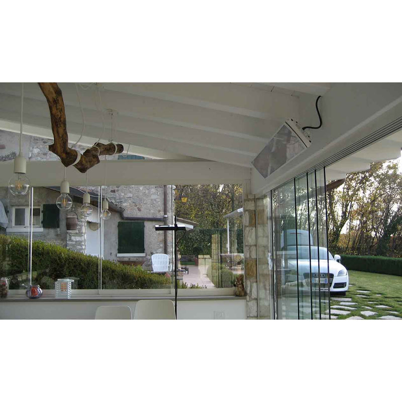 A white Heatscope Outdoor Vision 3200W heater providing warmth for a shed, with a larger house visible through the sheds glass, creating a cozy outdoor living space.