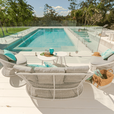 White & grey modular outdoor wicker lounge set poolside in an Australian backyard with the sunshine beaming.