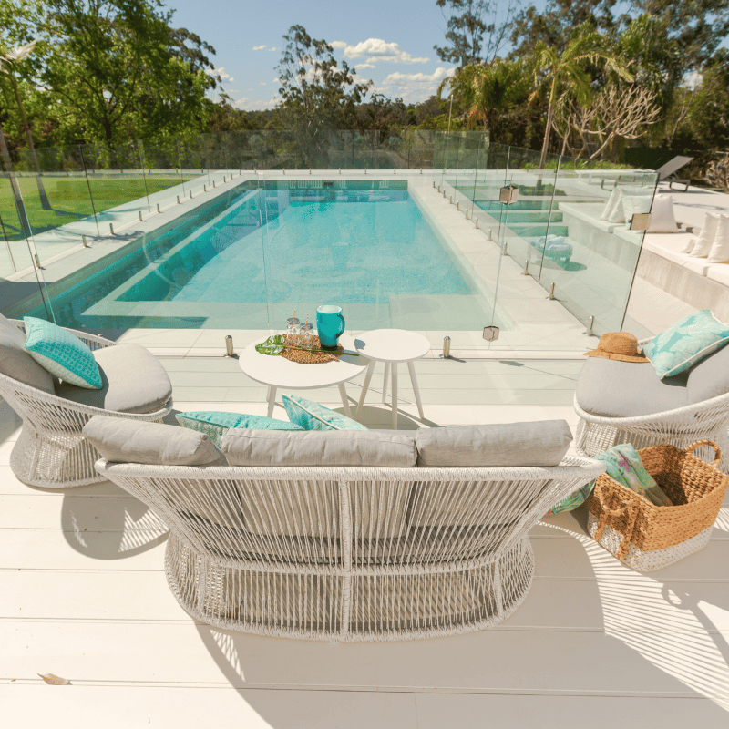 White & grey modular outdoor wicker lounge set poolside in an Australian backyard with the sunshine beaming.
