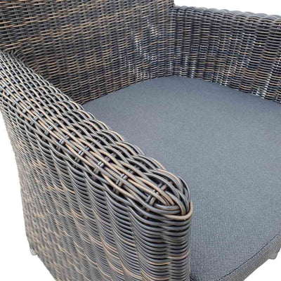 A close-up view of a wicker dining chair with charcoal frame and dark grey fabric set against a white background. Outdoor furniture, outdoor chairs, outdoor balcony furniture.