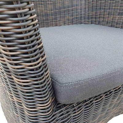 A close-up view of a wicker dining chair with charcoal frame and dark grey fabric set against a white background. Outdoor furniture, outdoor chairs, outdoor balcony furniture.