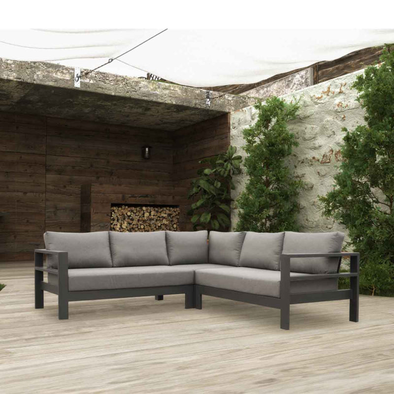 Outdoor furniture: An aluminium 5-seater Modular Lounge with charcoal frame and charcoal fabric set outdoors with greens and a woodpile in the background.